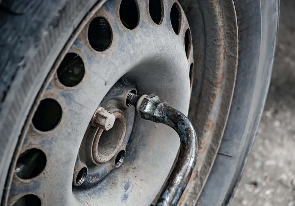 Auto mechanic changes wheel on old car.